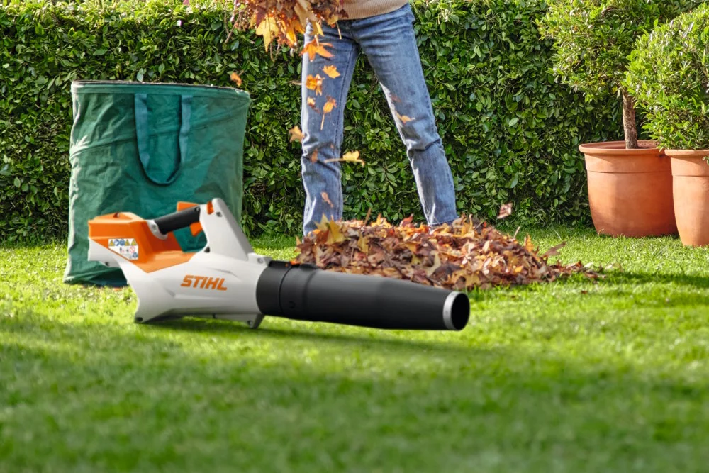 Person verwendet Laubsauger im Garten